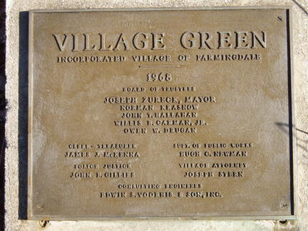 A wall-mounted plaque displaying an inscription and ornamental design.